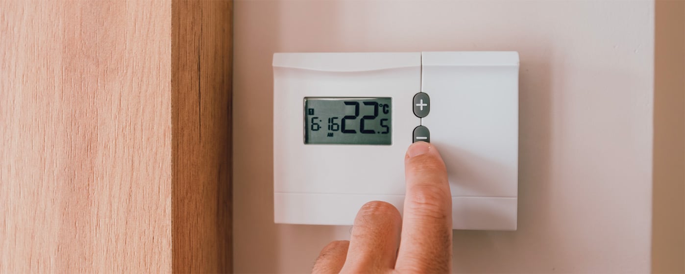 main réglant la température sur un thermostat